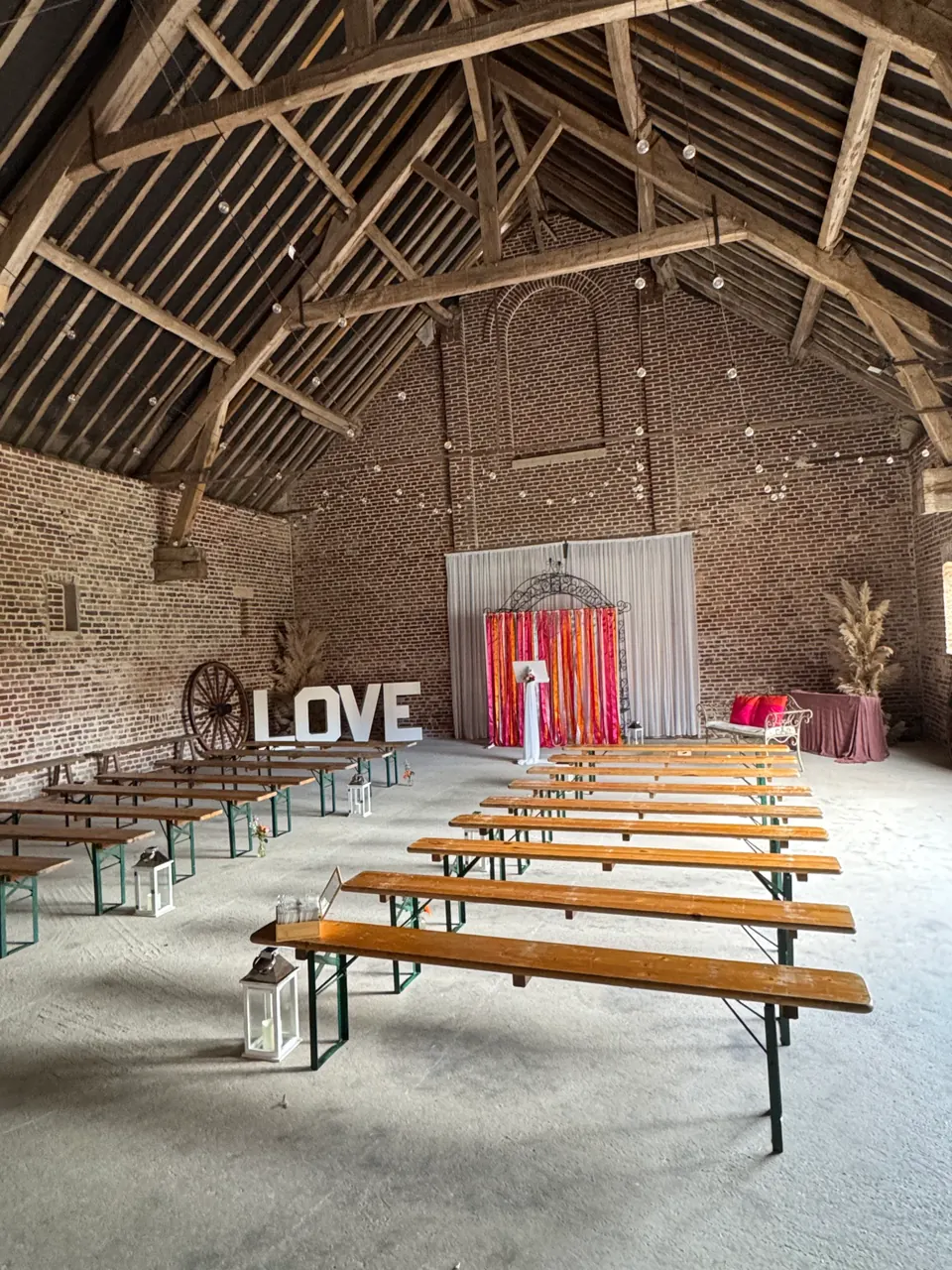 Salle de mariage aménagée dans une grange avec bancs et espace photo