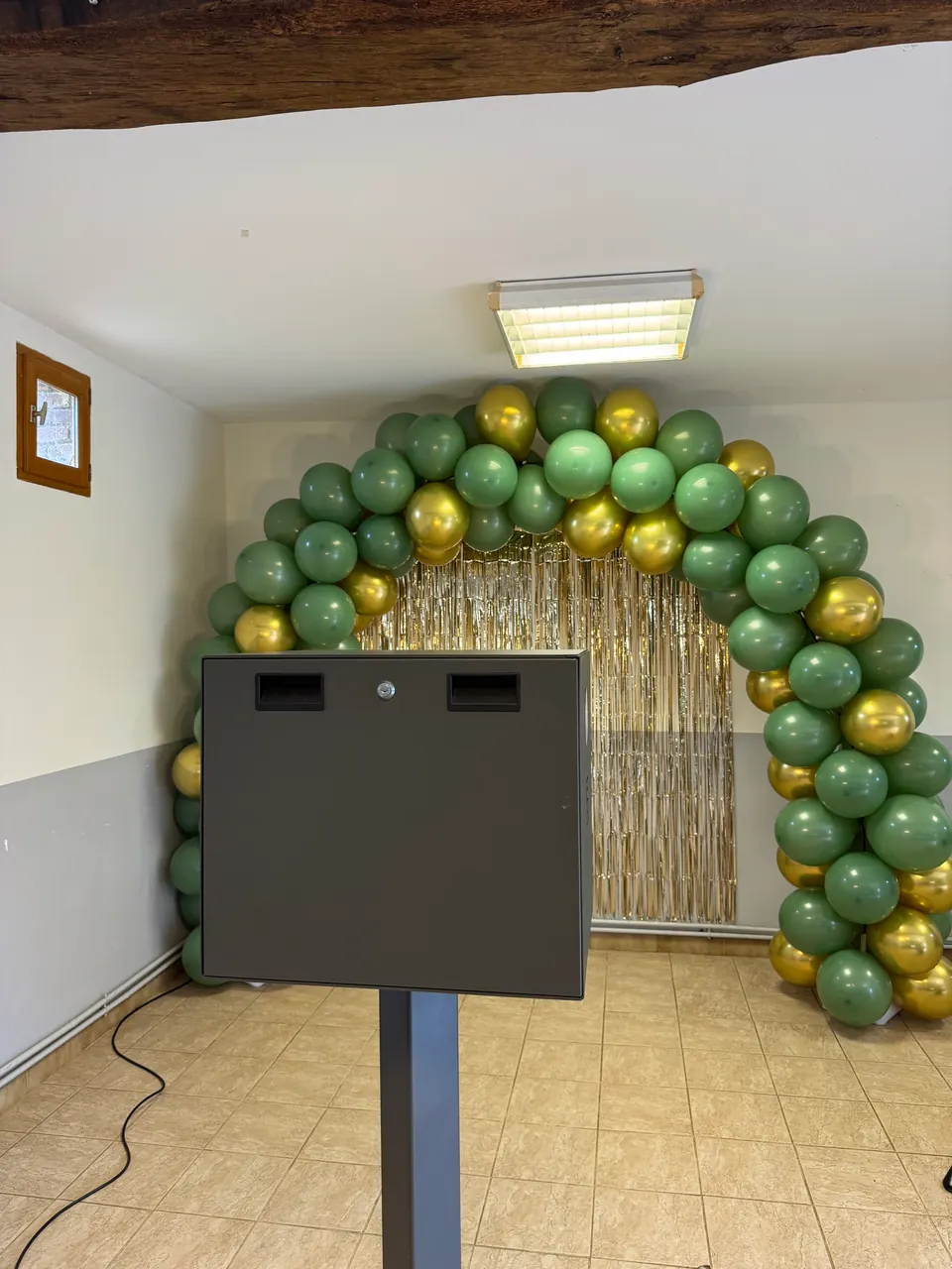 Photobooth installé devant une arche de ballons verts et dorés